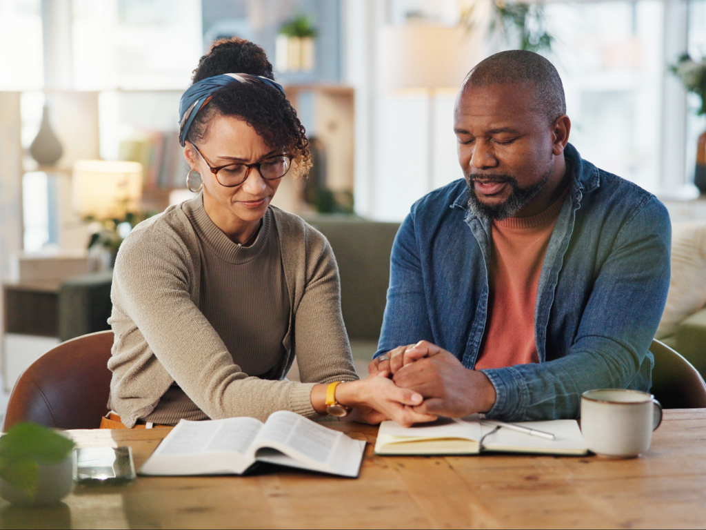 Couple praying together over an open Bible